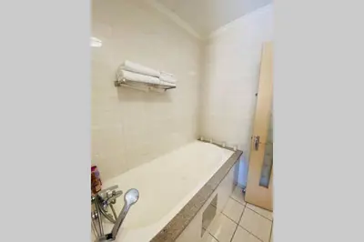 a white bathroom with a tub and a shower at Phoenix Rising Apartment in Midrand