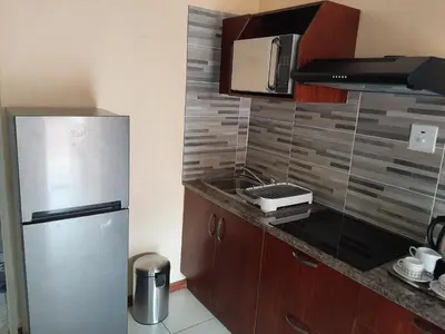 a kitchen with a refrigerator and a microwave at Lesedi Self Catering in Pretoria