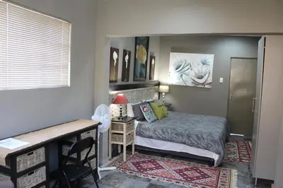 a bedroom with a bed and a table and a desk at Tucked-Away 1&2 Bedroom Houses in Nelspruit