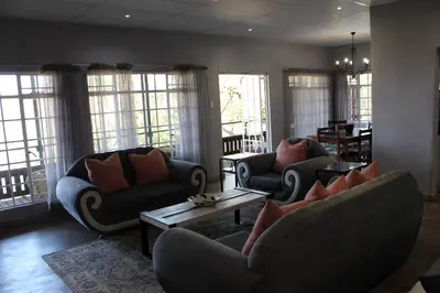 a living room with couches and tables and windows at Tucked-Away 1&2 Bedroom Houses in Nelspruit