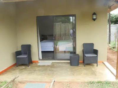 a room with two chairs and a bed and a mirror at Bongan Safari Lodge in Mbabat