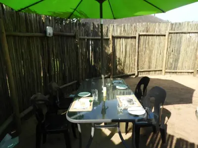 a table with chairs and an umbrella on a patio at Bongan Safari Lodge in Mbabat