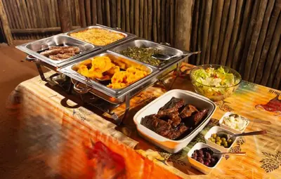 a table with several trays of food on it at Bongan Safari Lodge in Mbabat