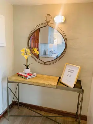 a table with a mirror on a wall with a table with a mirror at The Loft@Santorini in Pretoria