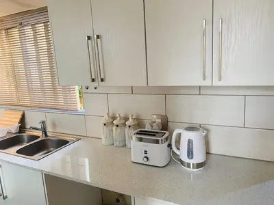 a kitchen with white cabinets and a toaster on a counter at The Loft@Santorini in Pretoria