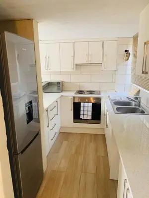 a kitchen with white cabinets and a stainless steel refrigerator at The Loft@Santorini in Pretoria