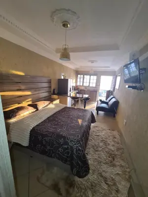 a bedroom with a large bed and a living room at SummerField Guest House in eNyamazaneni