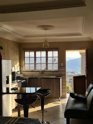 a kitchen with a table and some chairs in a room at SummerField Guest House in eNyamazaneni