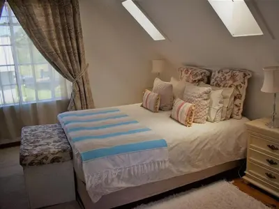 a bedroom with a bed with pillows and a window at Dullstroom Artist Cottages in Dullstroom