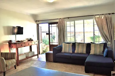 a living room with a couch and a tv at Dullstroom Artist Cottages in Dullstroom
