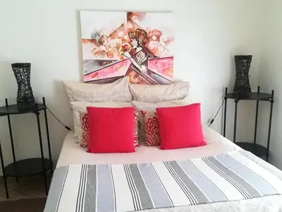 a bed with red pillows and a painting on the wall at Dullstroom Artist Cottages in Dullstroom
