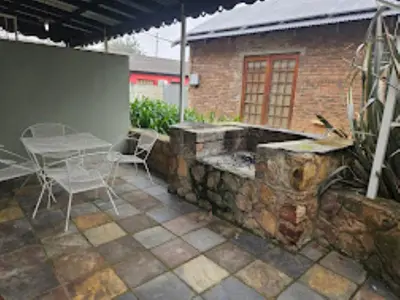 a patio with a table and chairs and a brick building at Dullstroom Artist Cottages in Dullstroom