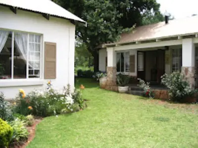 a white house with a yard with flowers at Dullstroom Artist Cottages in Dullstroom