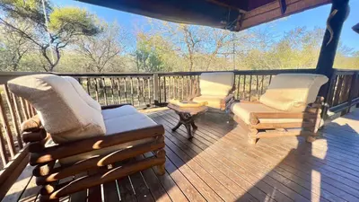 a porch with two rocking chairs and a table at Kruger Kumba - Mugwenzi in Marloth Park