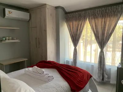 a bedroom with a bed with a red blanket on it at Waterfall View Lodge in Midrand