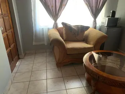 a living room with a chair and a window at Waterfall View Lodge in Midrand