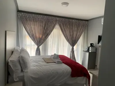 a bedroom with a large bed with a window at Waterfall View Lodge in Midrand
