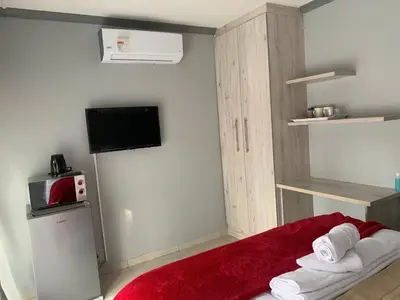 a small room with a bed with a red rug at Waterfall View Lodge in Midrand