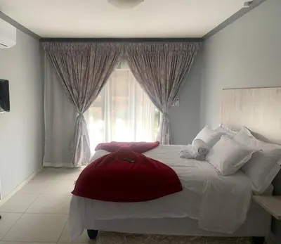 a bedroom with a large bed with a large window at Waterfall View Lodge in Midrand
