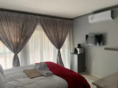 a bedroom with a bed and a window at Waterfall View Lodge in Midrand