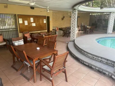 a patio with a table and chairs and a swimming pool at Rosscos Lodge in Phalaborwa