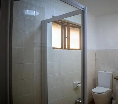 a bathroom with a toilet and a glass shower door at Kruger Park Lodge Unit 245 in Hazyview