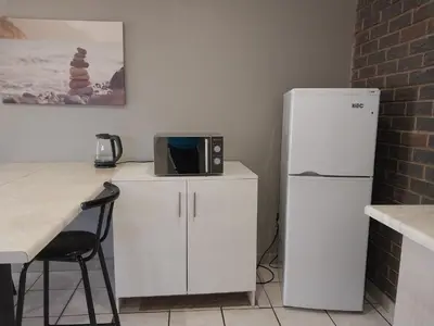 a kitchen with a white refrigerator and a microwave at Ratel Street Guesthouse in Pretoria