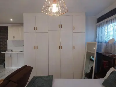a bedroom with white cabinets and a bed and a chandelier at Ratel Street Guesthouse in Pretoria