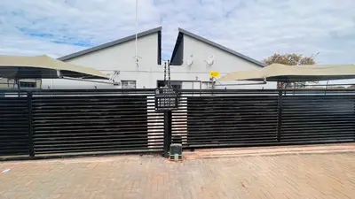 a black fence with a sign in front of a building at Zinathi Lodge in Polokwane
