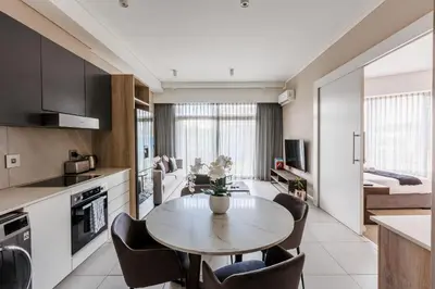 a kitchen and living room with a table and chairs at The Menlyn Main Residents Trilogy in Pretoria