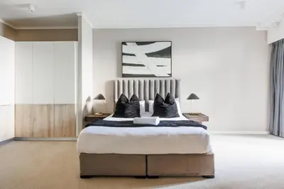 a bedroom with a large bed with black pillows at The Menlyn Main Residents Trilogy in Pretoria