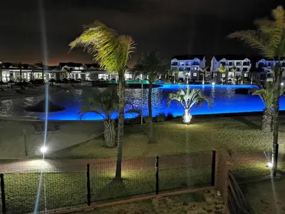 a view of a pool at night with palm trees at The Blyde Beach View in Pretoria