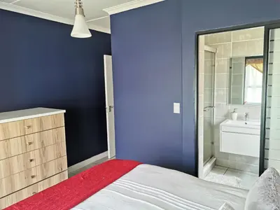 a blue bedroom with a bed and a bathroom at The Blyde Beach View in Pretoria