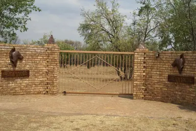 a brick fence with a gate with birds on it at Beka Idube Bushveld Retreat in Cullinan