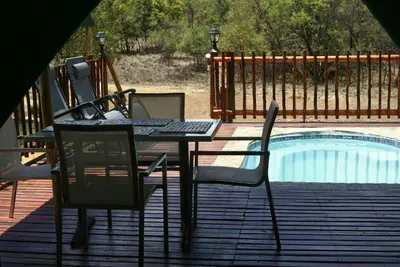 a table and chairs on a deck next to a pool at Beka Idube Bushveld Retreat in Cullinan