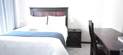 a hotel room with a bed and a desk at M n M Guesthouse Polokwane Central in Polokwane