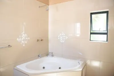 a white bathroom with a tub and a window at M n M Guesthouse Polokwane Central in Polokwane
