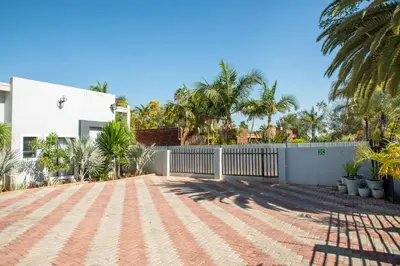 a driveway in front of a house with palm trees at M n M Guesthouse Polokwane Central in Polokwane