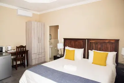 a bedroom with a large bed with yellow pillows at M n M Guesthouse Polokwane Central in Polokwane