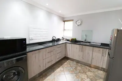 a kitchen with a sink and a washer and dryer at 7 At Brainline in Pretoria