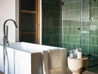 a bathroom with a white tub and green tiles at Askara Haus in Pretoria