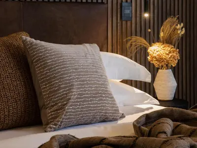 a bed with a pillow and a vase on a table at Askara Haus in Pretoria