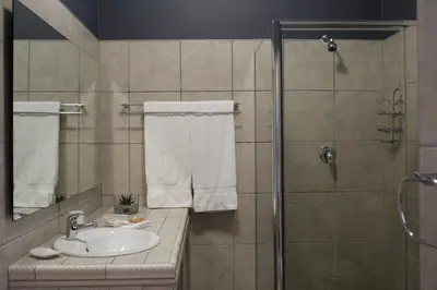 a bathroom with a sink and a shower with towels at Lindekroon Guest House in Polokwane