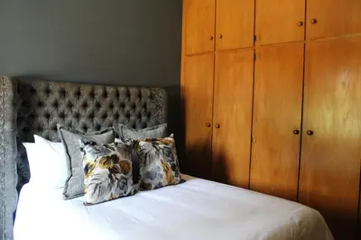 a bedroom with a large bed with pillows and aventory at Lindekroon Guest House in Polokwane