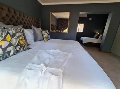 a large white bed in a bedroom with a mirror at Lindekroon Guest House in Polokwane
