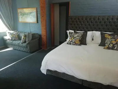 a bedroom with a large white bed and a couch at Lindekroon Guest House in Polokwane