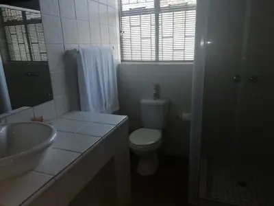 a white bathroom with a toilet and a sink at Lindekroon Guest House in Polokwane