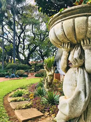 a statue in a garden with a bird bath at Lindekroon Guest House in Polokwane