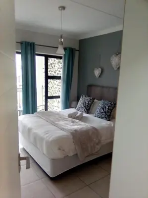 a bedroom with a bed with blue walls and a window at The Blyde in Pretoria
