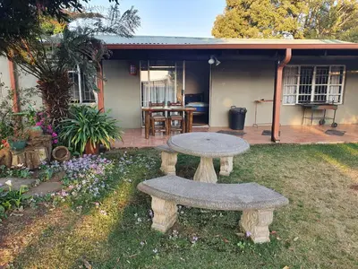 a table and bench in the yard of a house at Kaapsche Draai in Kaapsehoop